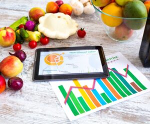 Gesunde Lebensmittel und Tablet mit einer Übersicht der Vitamine