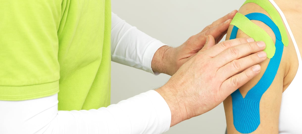 Chiro Taping Therapie mit mehreren farbigen Tapes zur Entlastung der Schulter